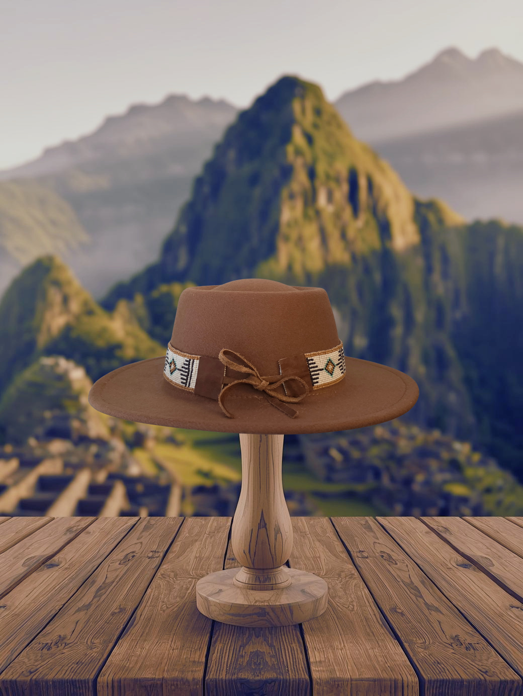 A brown wide-brim fedora hat with a decorative band and bow, displayed on a wooden stand over a rustic wooden table with a blurred mountain landscape background.